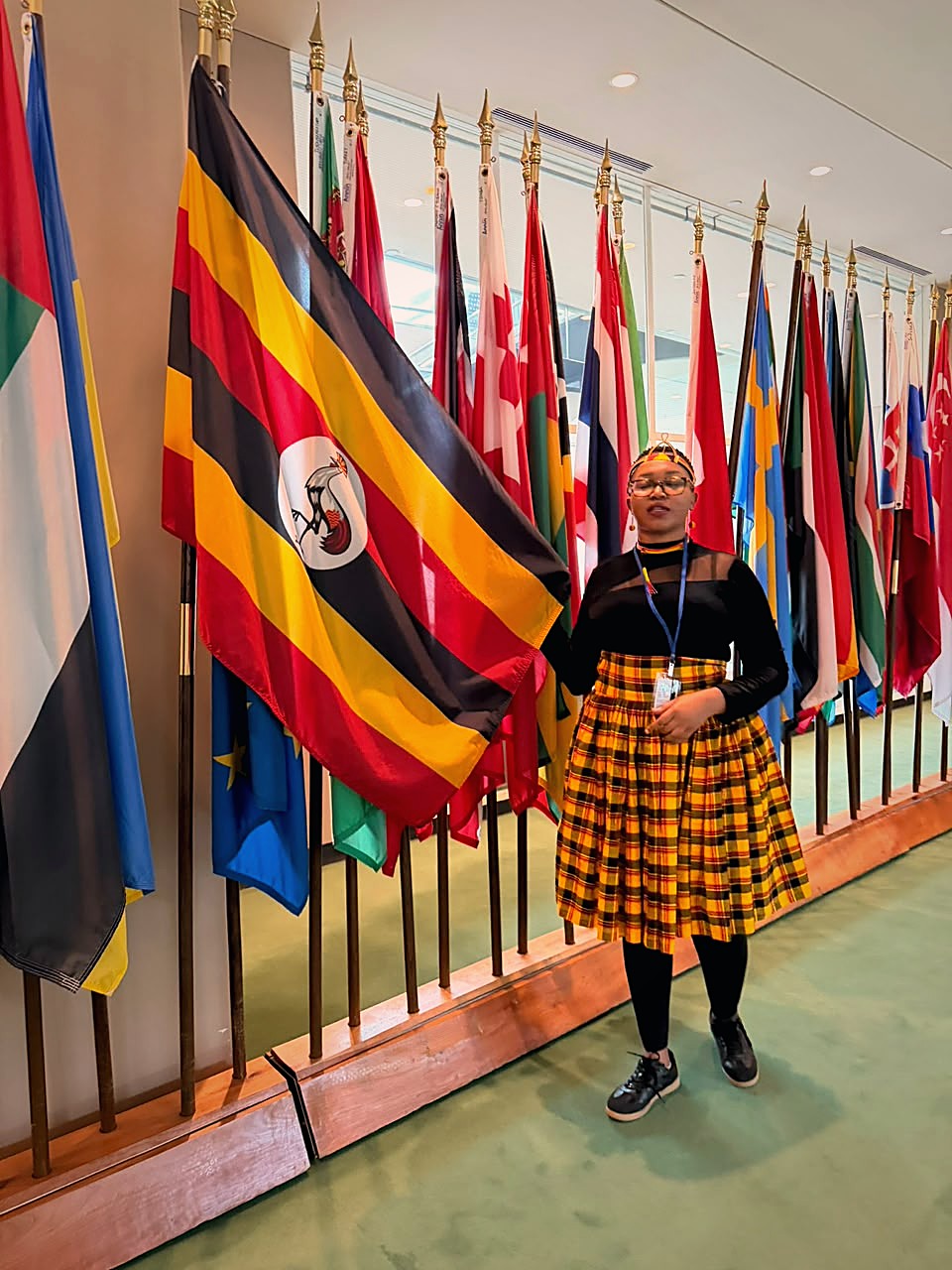 Brenda Kiconco beside the Uganda flag at the United Nations